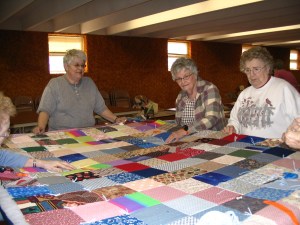 Colorful quilts are tied on a quilting frame.